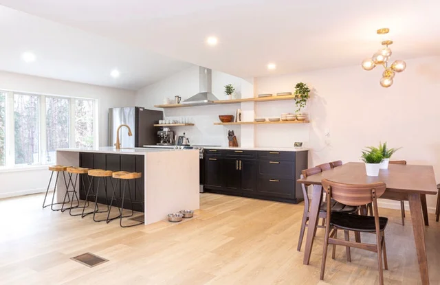 Modern kitchen with black cabinetry, wood island, floating shelves, and oak hardwood flooring