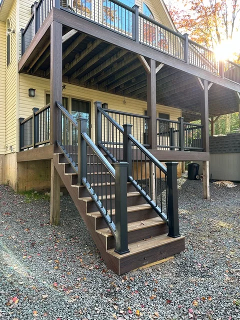 Two-tier composite deck with black railings, integrated stairs, and aluminum balusters