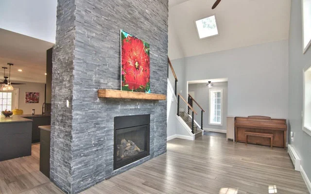 Slate tile fireplace with wood mantel, wood flooring, and open kitchen layout